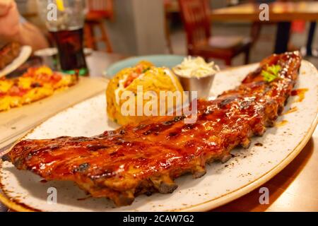 A rack of oven barbecue ribs glazed with sauce on a plate in a restaurant Stock Photo