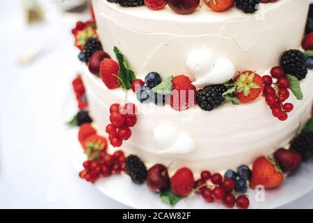 Close up of elegant white wedding cake decorated with various berries at reception Stock Photo