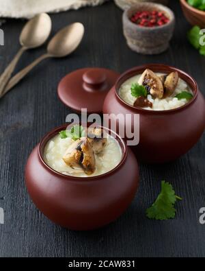Unconventional unusual serving of risotto with mushrooms in pot. Rice porridge with mushrooms. Stock Photo