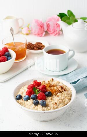 Oatmeal porridge with blueberry, raspberries, side view, vertical. Healthy breakfast with berries Stock Photo