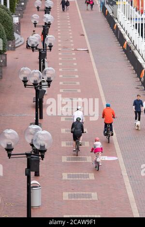 Looking down from behind on three adults and one child riding bicycles in winter time in Sydney at Darling Harbour, Australia Stock Photo