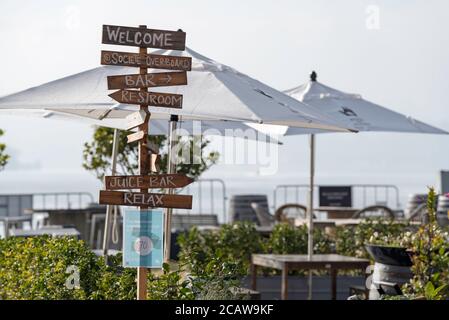 A welcome sign stands outside the all but empty alfresco cafe restaurant on Cockatoo Island in Sydney Harbour on a foggy winters morning Stock Photo