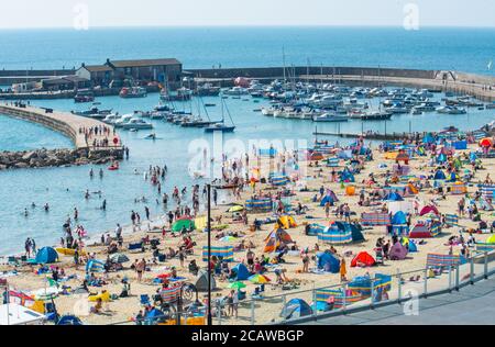 Lyme Regis, Dorset, UK. 9th Aug, 2020. UK Weather: Holidaymakers and sunseekers pack out the beach again on Sunday to bask in another day of scorching hot sunshine as the summer heatwave continues. Beachgoers flock to coastal resorts on the South Coast to soak up the record breaking hot sun and sizzling hot temperatures. Credit: Celia McMahon/Alamy Live News Stock Photo