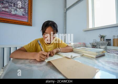 (200809) -- XILIN GOL, Aug. 9, 2020 (Xinhua) -- Xilinhua does homework at home in Xilinhot, north China's Inner Mongolia Autonomous Region, Aug. 4, 2020. Summer vationtion has been Xilinhua's favorite time of year. In order to attend middle school, the 14-year-old lives most of the time with her grandparents in downtown Xilinhot, separated from her parents who run a ranch on the Baiyinxile pasture. Therefore, summer means both relaxation and reunion to the seventh grader.   Xilinhua's father Gangsuhe is a famous horse rider. Learning from him, Xilinhua had also mastered equestrian skills when Stock Photo