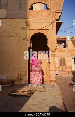 Jaisalmer / India - March 19, 2020: Indian woman in Jaisalmer with historic building of beautiful architecture Stock Photo