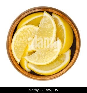 Lemon half in wooden bowl. Freshly cut ripe yellow edible citrus fruit. Citrus limon. Lemon juice is used for culinary purposes and for cleaning. Stock Photo