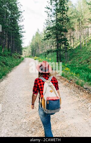 Young female nature explorer walking on mountain dirt road Stock Photo