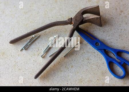 Closeup of old rusty plier scissors and screws on the ground Stock Photo