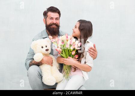 Wishing happy anniversary. Happy family celebrate anniversary. Father and daughter hold tulips and toy. Fathers day. Womens day. Birthday anniversary. Holiday celebration. International childrens day. Stock Photo