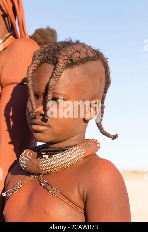 KAMANJAB, NAMIBIA - SEPTEMBER 07, 2015: Unidentified child Himba tribe with traditional ornaments and makeup living near Kamanjab. The Himba are indig Stock Photo