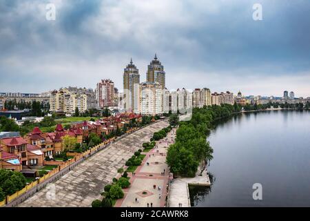 Aerial view on river Dnepr with cloudy sky and house district in green Obolon area of Kyiv city. Flying drone camera shot. Stock Photo