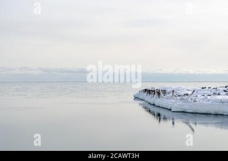 Winter beach, icicles, sea, rocks in the background, Tikhaya Bay, Sakhalin Island, Sea of Okhotsk Stock Photo