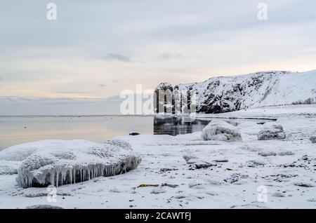 Winter beach, icicles, sea, rocks in the background, Tikhaya Bay, Sakhalin Island, Sea of Okhotsk Stock Photo