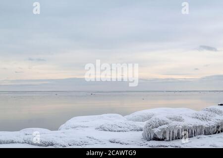 Winter beach, icicles, sea, rocks in the background, Tikhaya Bay, Sakhalin Island, Sea of Okhotsk Stock Photo