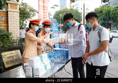 Hanoi, Vietnam. 9th Aug, 2020. Traffic police provide water for candidates of the High School Graduation Exam in the Vietnamese capital city of Hanoi on Aug. 9, 2020. Nearly 867,000 Vietnamese high school students started sitting for a national final exam on Sunday amid strict COVID-19 control measures, Vietnam News Agency reported. The annual exam for both high school graduation and university entrance consideration has been postponed for over a month due to complex developments of the COVID-19 pandemic in the country this year. Credit: VNA/Xinhua/Alamy Live News Stock Photo
