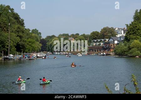 view from ham towards richmond, surrey, england, with canoeists, rowers and others on the river thames Stock Photo