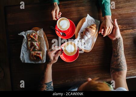 Top view of a man and woman on date in a cafe drinking coffee, holding hands Stock Photo