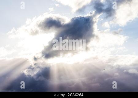 Sun rays bursting through a dark cloud with the silhouette of a bird visible. Royalty free stock photo. Stock Photo