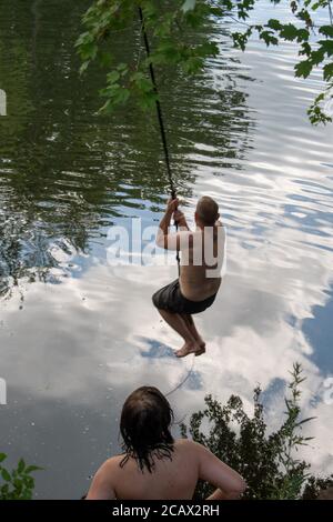 Swinging to dog days of summer on a rope swing Stock Photo