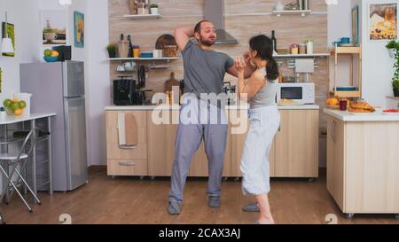 Married couple arguing at the kitchen during breakfast. Domestic violence threatening aggressive angry frustrated husband abusing physical depressed sad unhappy crying stressed woman. Home abuse Stock Photo