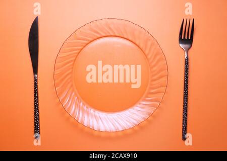 cutlery and empty plate on orange background top down Stock Photo
