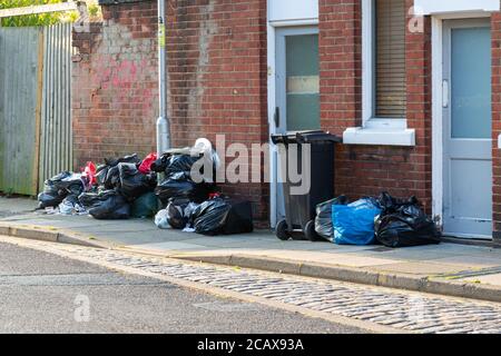 Plastic bin bags full of rubbish outside a home ready for collection by bin men on bin collection day Stock Photo