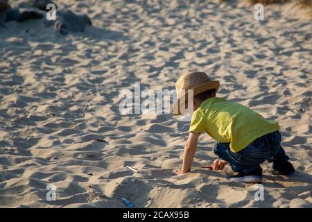 A small boy playing in a sandpit in a park during summer Stock Photo