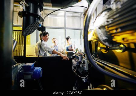 Factory owner showing control panel of new modern roaster to smiling excited entrepreneurs at meeting Stock Photo