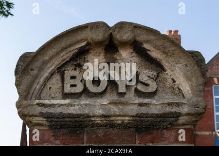A brick pillar outside a school with the words Boys a common sight on the entrance to a school in the Victorian era when children were segregated Stock Photo