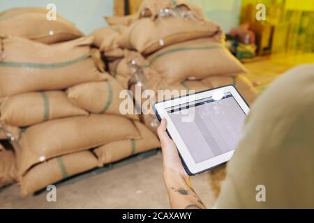 Businesswoman checking document on digital tablet when counting sackes in warehouse Stock Photo