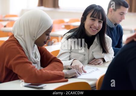 Exams Preparation. Group Of Multi-Ethnic Students Studying Together inside classroom while helping each other. Stock Photo
