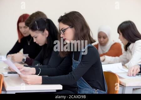 Exams Preparation. Group Of Multi-Ethnic Students Studying Together inside classroom while helping each other. Stock Photo