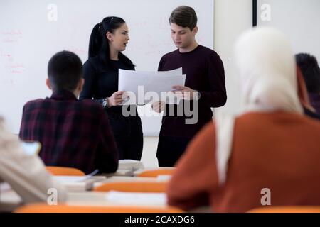 Exams Preparation. Group Of Multi-Ethnic Students Studying Together inside classroom while helping each other. Stock Photo