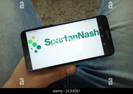 Man holding smartphone with SpartanNash company logo Stock Photo