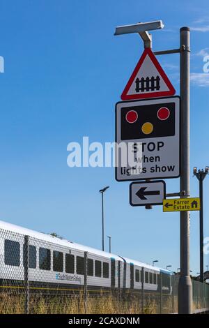 South Western Railway train approaching Wool train station with stop when lights show sign for level crossing at Wool, Dorset UK in August Stock Photo