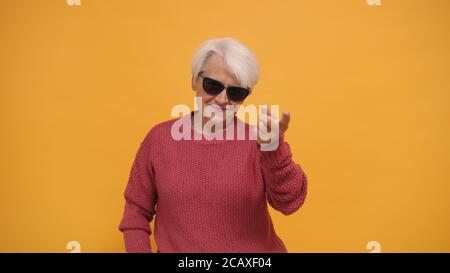 Senior gray haired woman with sunglasses and smile pointing finger to the camera. High quality photo Stock Photo