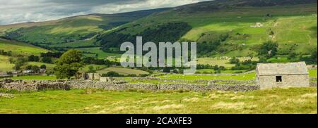 Swaledale in North Yorkshire.  A panorama of the Yorkshire Dales villages of Gunnerside and Muker with stone barn and drystone walling. Space for copy Stock Photo