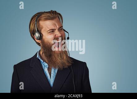 Young adult hipster man with headset working as operator annoyed, frustrated shouting with anger, crazy and yelling, angry customer service representa Stock Photo