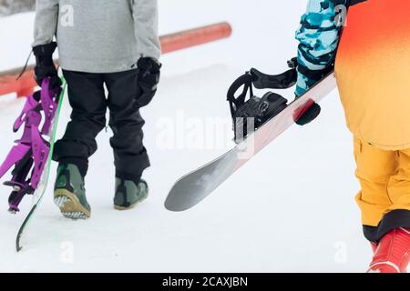 two snowboarders walking on a warm winter day, close up cropped photo. free time, hobby Stock Photo