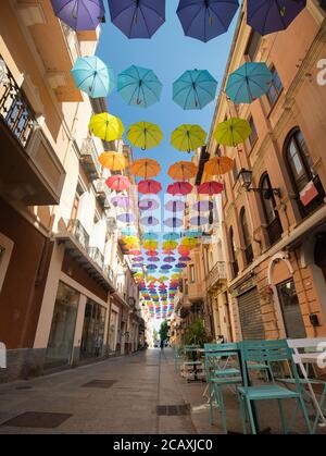 glesias, Italy: Colorful umbrellas hanging over a street in old Iglesias city in a sunny day Stock Photo