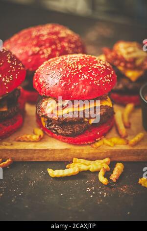 A set of red bun homemade delicious burgers of beef, bacon, cheese, grilled onion on a dark rusty Stock Photo