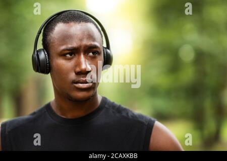 Portrait of concentrated black guy with wireless headset, training outdoors Stock Photo