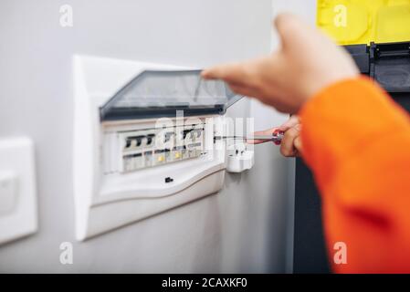 Electrician installing panel with electric meter in apartment of customer Stock Photo