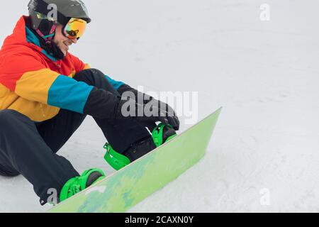 cheerful active sportsman trying on boots before snowboarding. close up photo. copy space Stock Photo