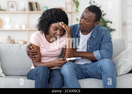 African man hugging his upset wife, having negative pregnancy test Stock Photo