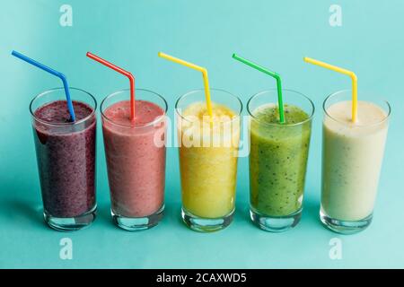 glasses with fresh delicious smoothie and straw on isolated blue background. health and body care Stock Photo