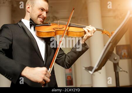 young caucasian talented gorgeous man un tux play violin, professional musician practice performance, use classic instrument . music concept Stock Photo