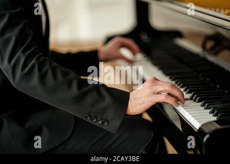 young talented male in formal suit professionally play piano. classical music performer practice playing piano before performance Stock Photo