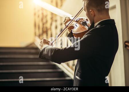 young caucasian talented gorgeous man un tux play violin, professional musician practice performance, use classic instrument . music concept Stock Photo