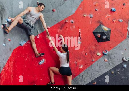 Handsome young man and long-haired woman exercising at fitness centre. Physical challenge. Brave woman. Stock Photo